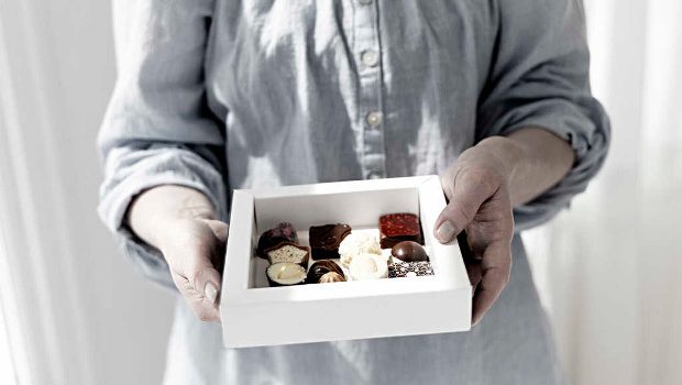 A woman holding a carton board box with chocolates.