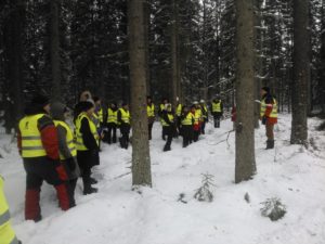 Ihmisjoukko tutustumassa metsienhoitoon talvisessa metsässä.
