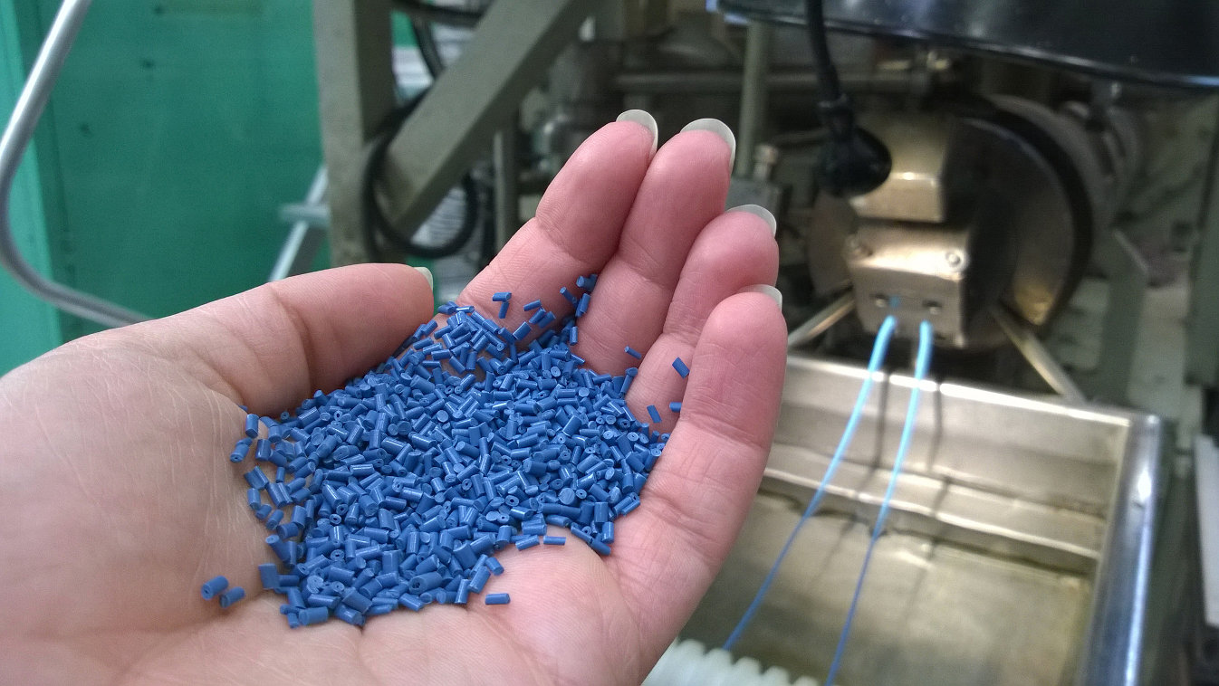Sinisiä biopohjaisia muovirakeita kämmenellä.