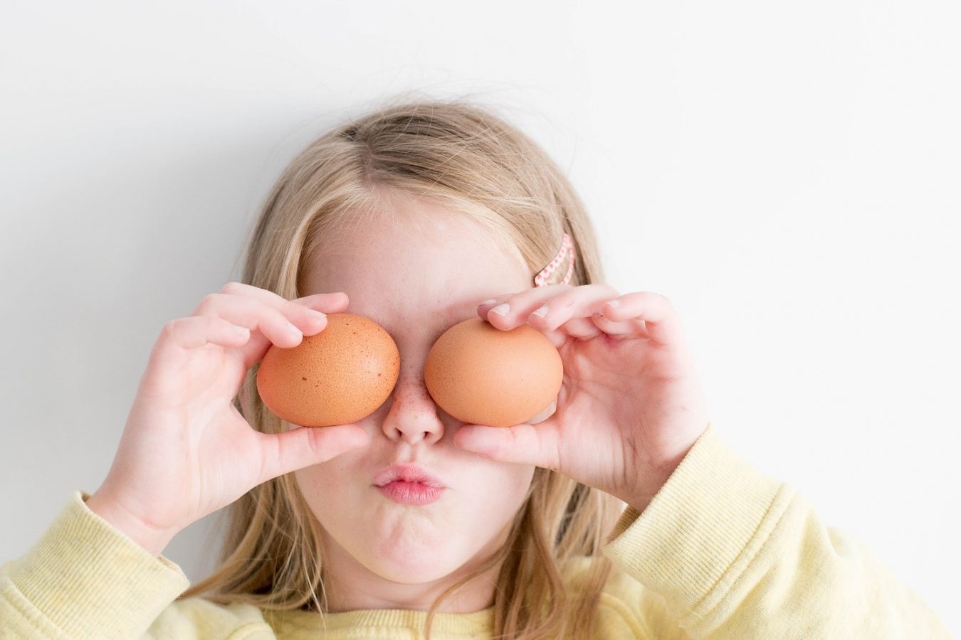 Lapsi pitää kananmunia silmien edessä.