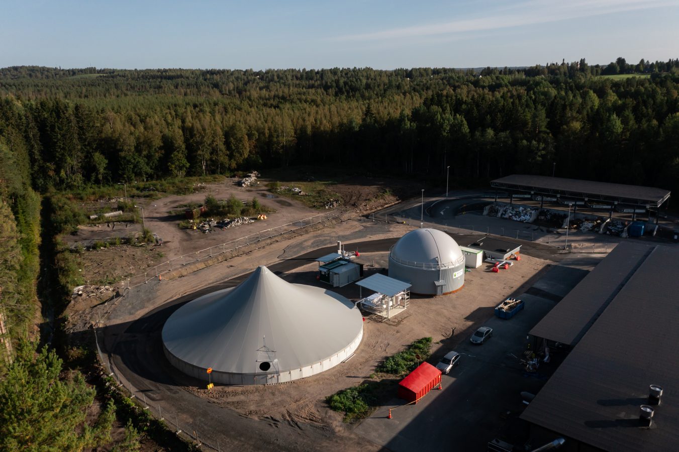 Ilmakuva biokaasulaitoksessa. Kuvassa näkyy pyöreä, telttamainen rakennus ja sen rinnalla pienempiä rakennuksia. Taustalla näkyy metsää.