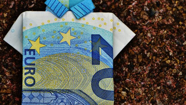 Kahdenkymmenen euron setelistä taiteltu lyhythihainen kauluspaita. Tausta ruskeaa kiveä.